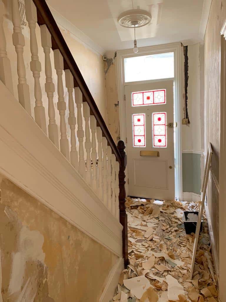 This is a photo of a hallway where the walls and ceiling are being stripped back, and re-wiring is being carried out, ready for bonding and re-plastering