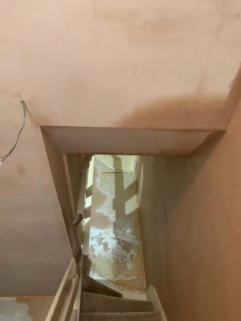 This is a photo of a hallway that has been re-plastered. The walls and ceilings were plastered, and are drying.